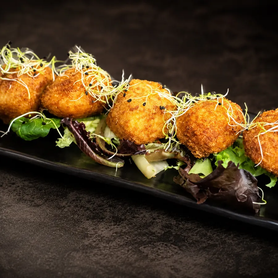 Croquetas caseras emplatadas con brotes verdes